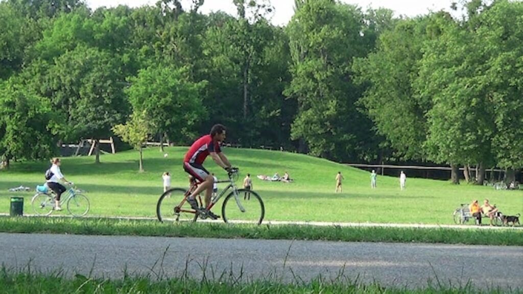 Radfahrer fährt auf einem Weg durch eine grüne Parklandschaft